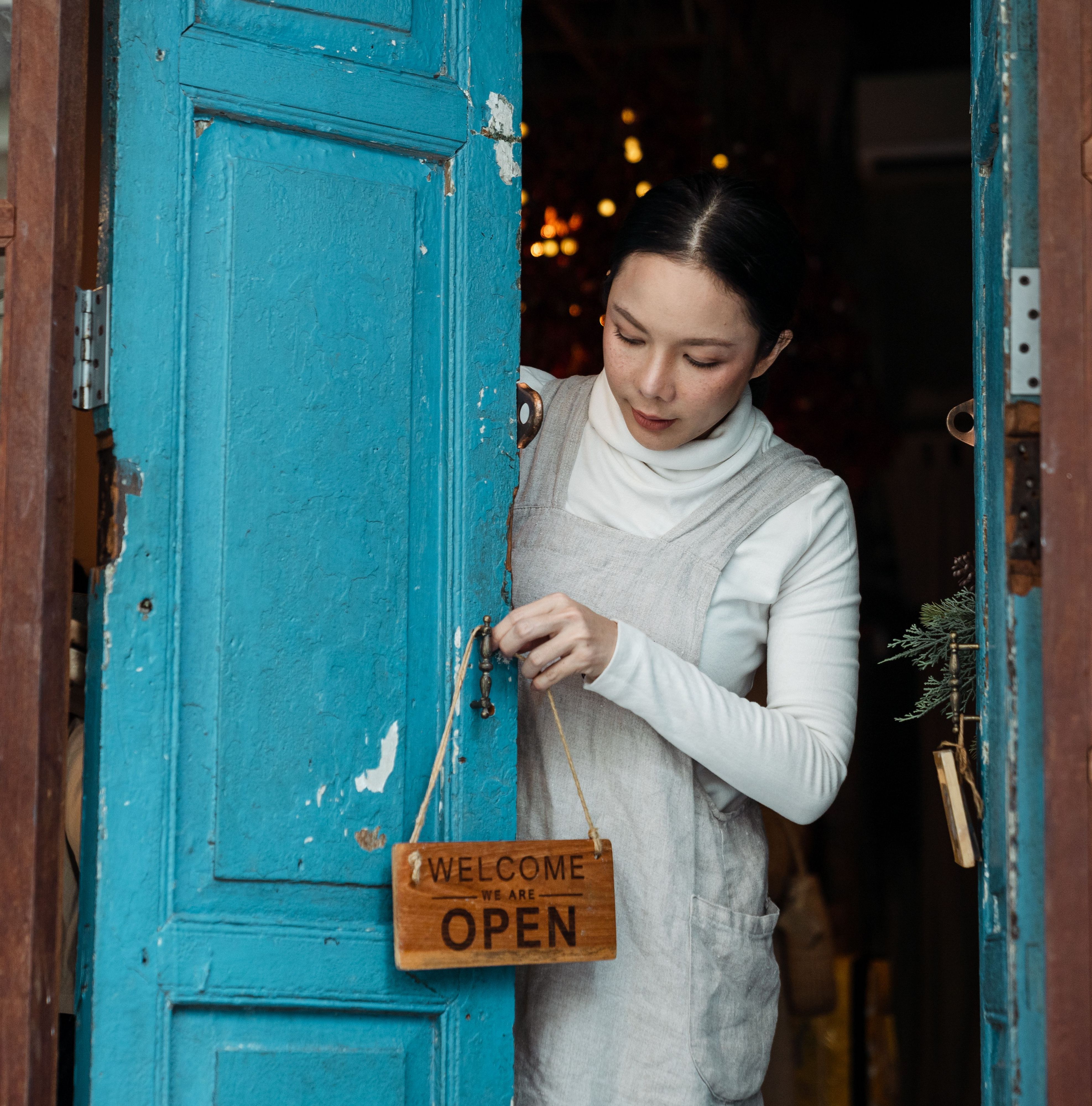Entrepreneur opening the door of his shop with an "Open" sign.